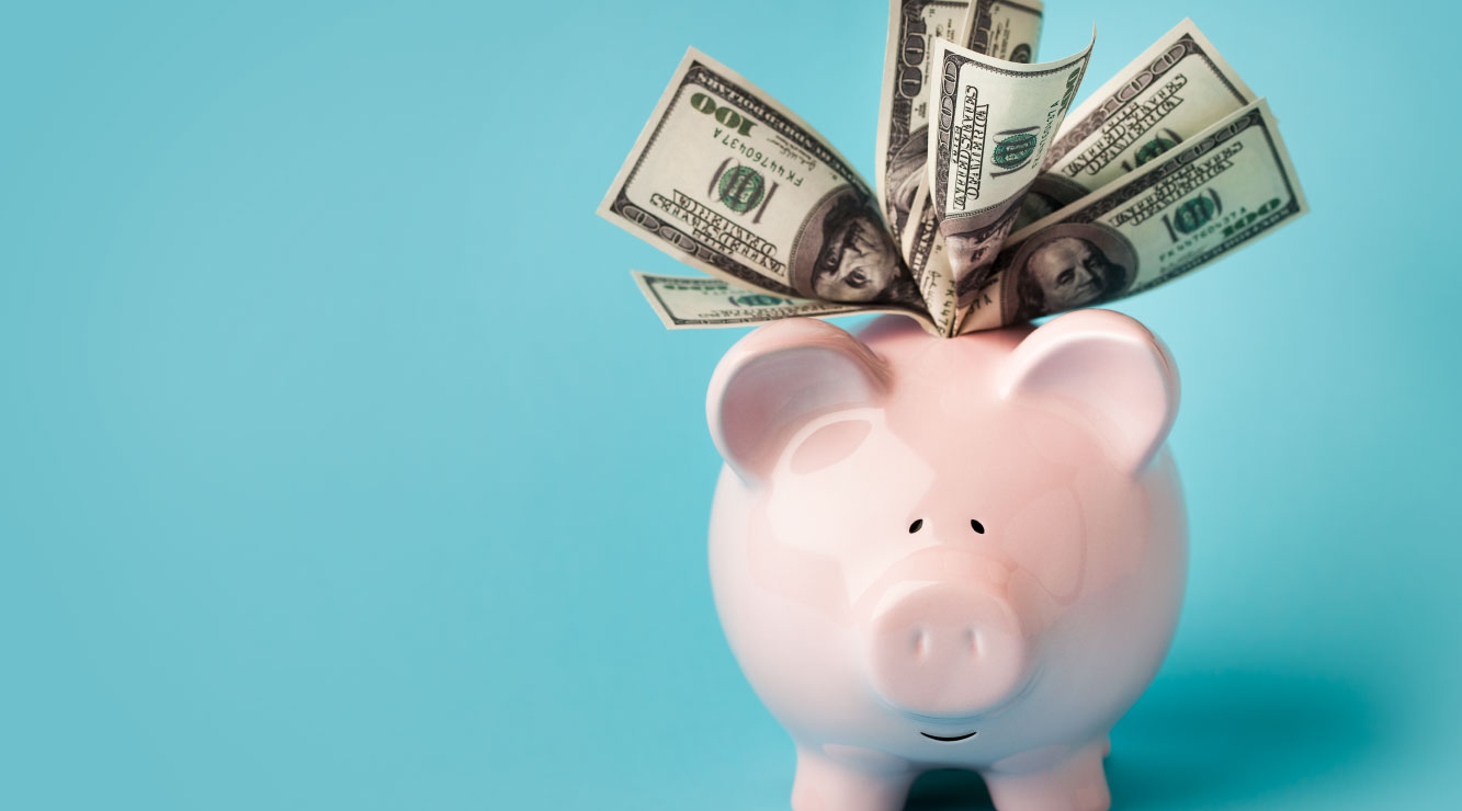 Image of a teal background with a pink piggy bank.  $100 bills are sticking out of the top of the piggy bank.