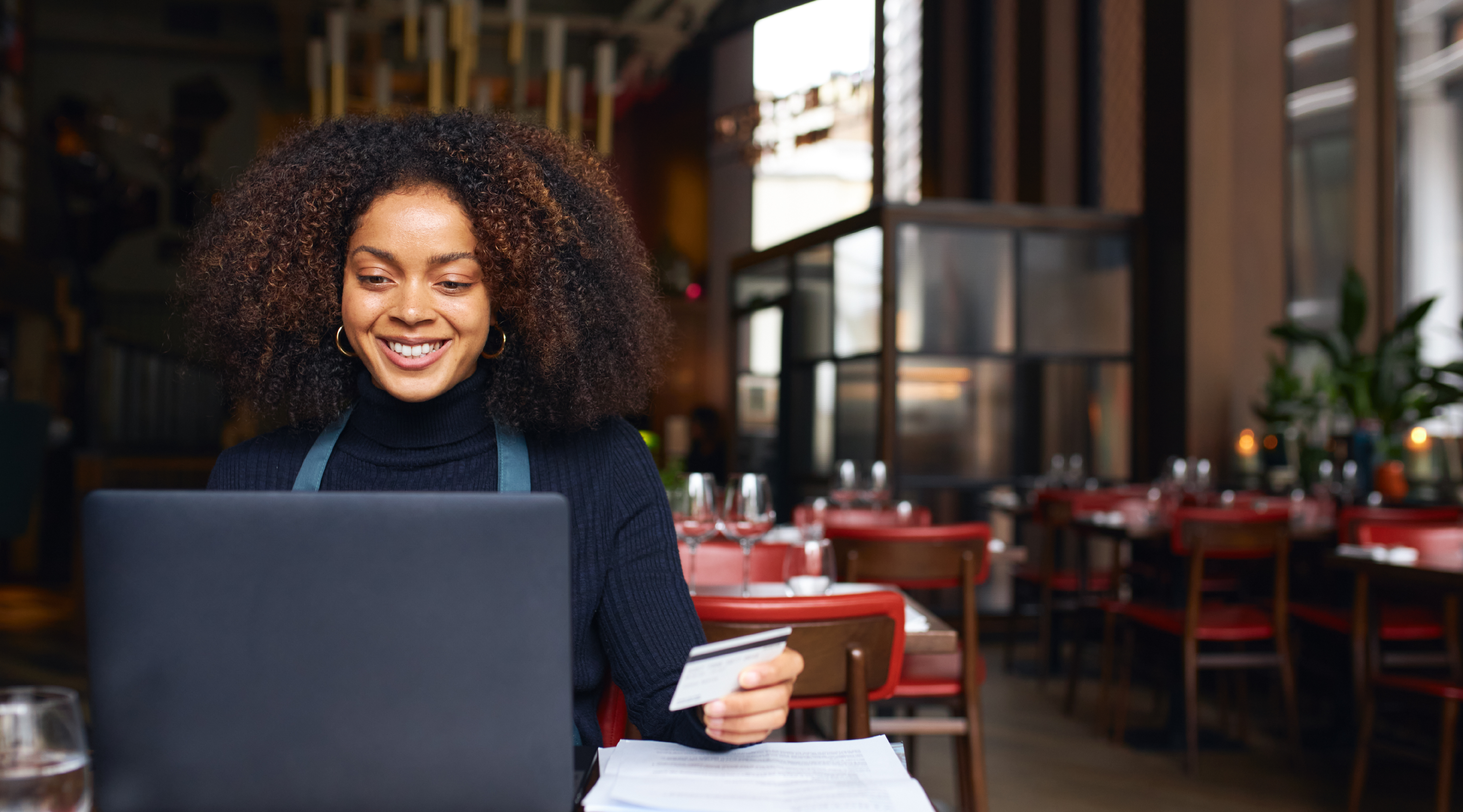 Image of lady working on her laptop, holding her card.