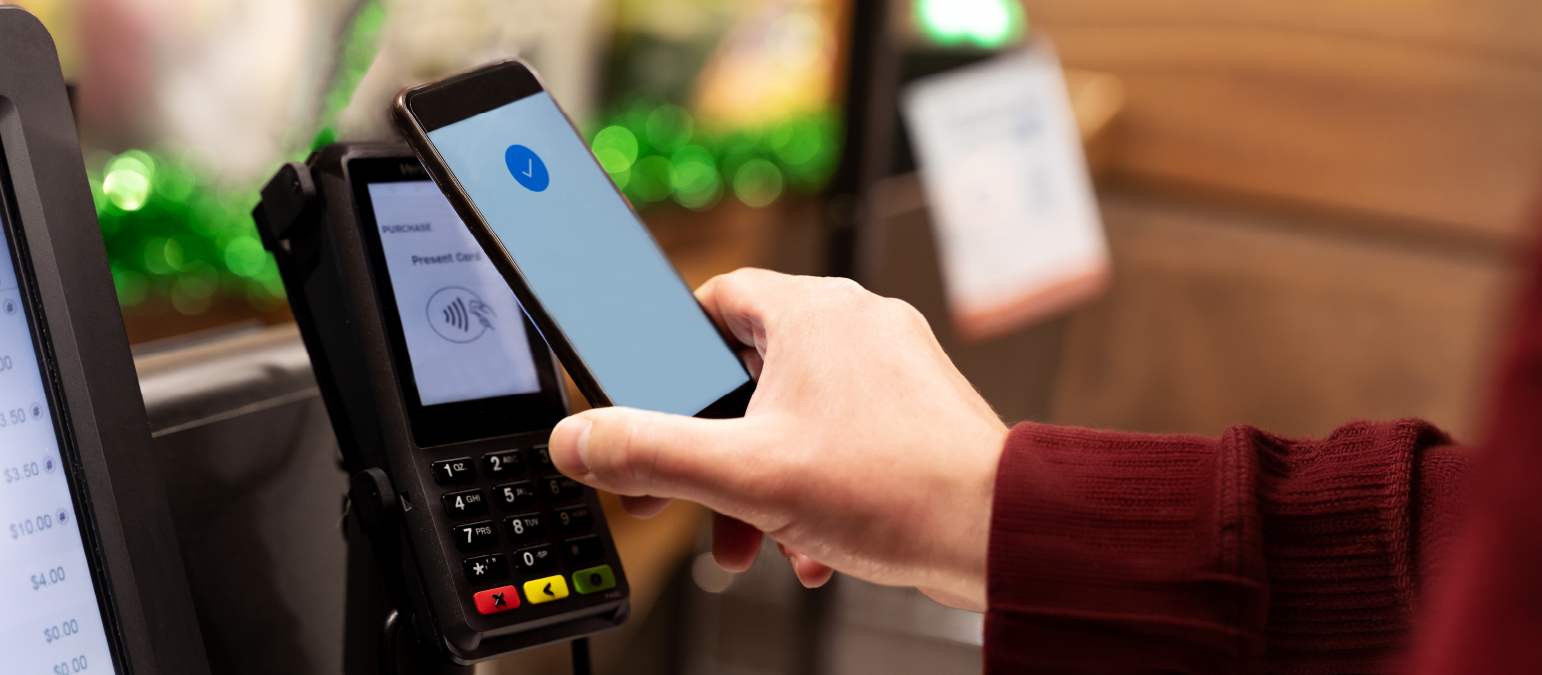 Image of a phone being held near a payment kiosk.