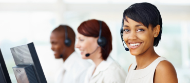 Three people in white shirts working a call center wearing headsets