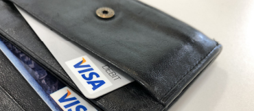 Image of an open black wallet and 2 Visa credit cards displaying in the card pockets of the wallet.