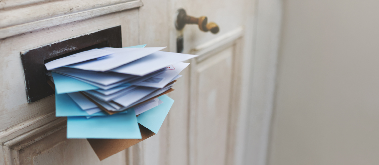 Image of many pieces of mail sticking out of a mail slot.